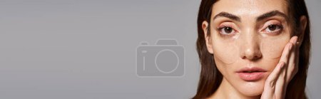 Una joven con el pelo moreno muestra una belleza impresionante en parches para los ojos, mirando a la cámara, pancarta