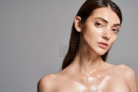 Eine junge kaukasische Frau mit brünetten Haaren und sauberer Haut, die mit Wassertropfen bedeckt ist und einen hypnotisierenden und erfrischenden Effekt erzeugt.