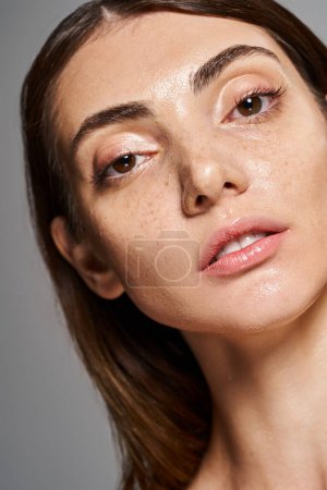 Close-up of a young caucasian woman with freckles on her face in a studio setting, showcasing her natural beauty.