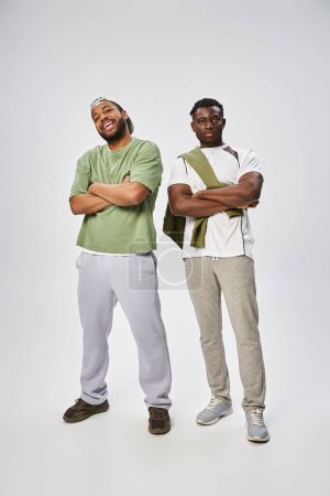 Concepto Juneteenth, dos amigos afroamericanos de pie con los brazos cruzados sobre fondo gris