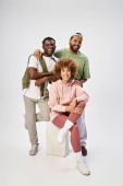 cheerful african american men posing near curly woman on grey background, Juneteenth celebration t-shirt #695321574