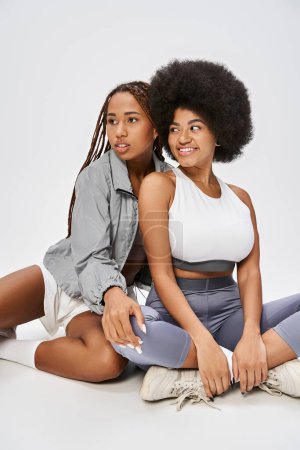 beautiful young african american women posing together on grey background, Juneteenth concept