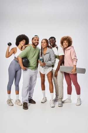 group of sportive african american friends standing with sports equipment on grey background