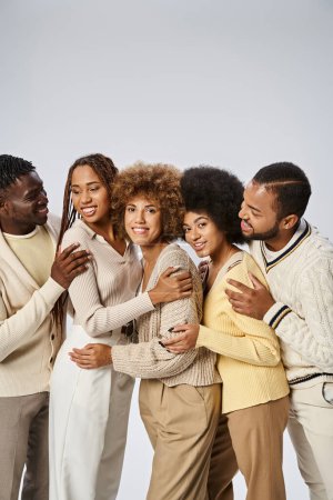 grupo de personas afroamericanas felices en traje elegante abrazándose sobre fondo gris, Juneteenth