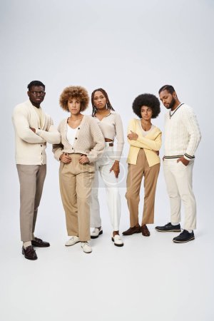 Gruppe junger afrikanisch-amerikanischer Männer und Frauen posiert gemeinsam auf grauem Hintergrund, Juni