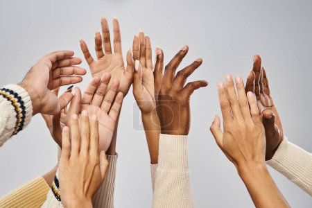 Schnappschuss einer afrikanisch-amerikanischen Gemeinschaft, die die Hände vor grauem Hintergrund ausstreckt, Juni