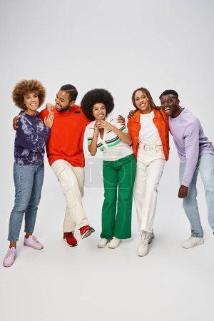 fröhliche afrikanisch-amerikanische Gemeinschaft in farbenfroher Freizeitkleidung, die zusammen auf grauem Hintergrund steht