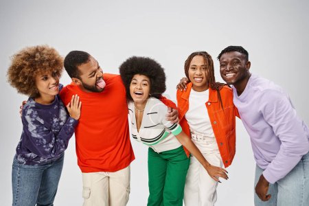 fröhliche afrikanisch-amerikanische Menschen in farbenfroher Freizeitkleidung, die gemeinsam Spaß auf grauem Hintergrund haben