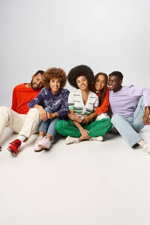 afrikanisch-amerikanische Freunde in farbenfroher Kleidung verbringen Zeit miteinander vor grauem Hintergrund, Juni