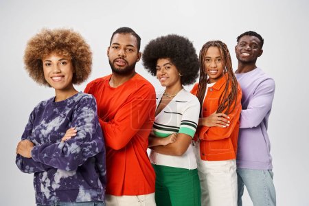 fröhliche afrikanisch-amerikanische Menschen in lässiger Kleidung posieren gemeinsam vor grauem Hintergrund, Konzept vom Juni