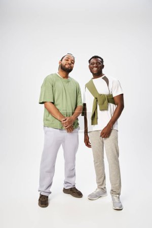 joyful african american men in casual wear standing together on grey background, Juneteenth
