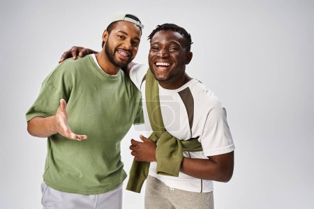 smiling african american male friends in casual wear hugging on grey background, Juneteenth