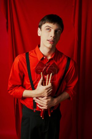 dreamy cupid in shirt and suspenders holding heart shaped arrows on red background, 14 February