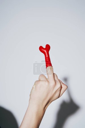 Foto de Vista recortada del joven provocador mostrando el dedo medio con globo rojo sobre fondo gris - Imagen libre de derechos
