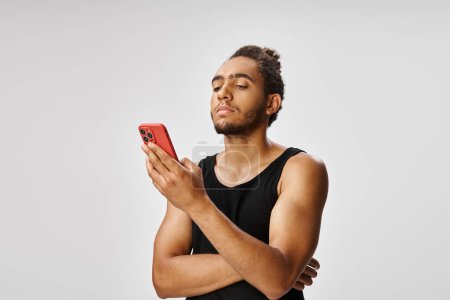bien parecido atlético afroamericano hombre mirando su teléfono inteligente, concepto de apuestas en línea