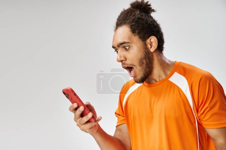 surprised african american man in sportwear looking at his smartphone, online betting concept