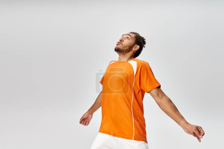 atractivo joven afroamericano jugador de fútbol en ropa deportiva posando en acción sobre fondo gris