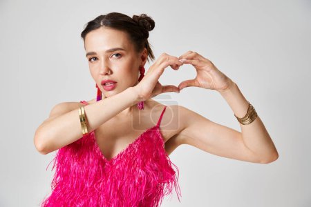 Pretty brunette woman with pierced nose  wearing pink feather dress showing a hand heart to camera
