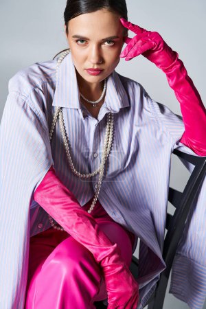 Brünette Frau mit rosa Handschuhen und stylischem Outfit, berührt ihre Stirn