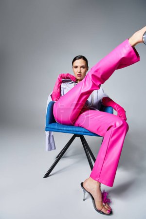 Foto de Mujer morena confiada en pantalones y zapatos rosas de moda, sentada y pateando su pierna - Imagen libre de derechos