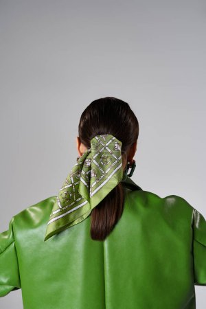 Téléchargez les photos : Vue arrière de la femme brune portant une veste en cuir vert et un foulard en studio - en image libre de droit