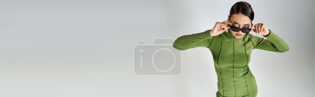 Photo for Top view of woman in green outfit, touching eyewear with both hands and looking at camera, banner - Royalty Free Image
