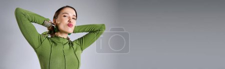 Téléchargez les photos : Portrait de femme brune fantaisie dans le vert total look branché baisers soufflant à la caméra, bannière - en image libre de droit
