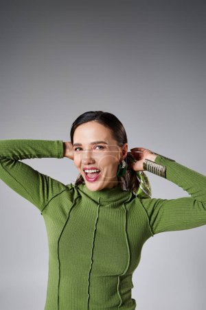 Portrait of cheerful smiling woman in green trendy outfit laughing isolated on grey background