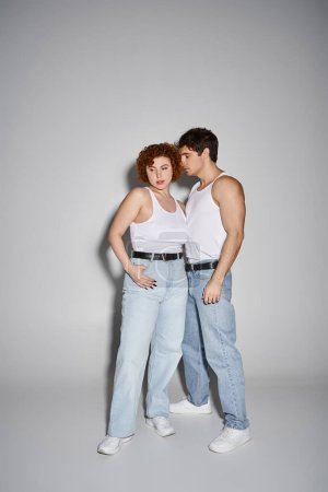 atractivo sexy pareja en azul jeans posando juntos amorosamente sobre gris fondo, relación