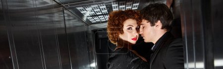 Téléchargez les photos : Couple passionné en robe élégante et costume étreignant dans l'ascenseur et regardant la caméra, bannière - en image libre de droit