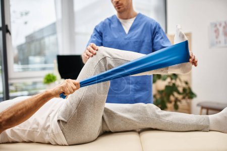 cropped view of dedicated doctor in blue uniform helping his mature patient to use resistance band