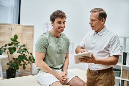 good looking mature doctor checking up knees of his patient in hospital, rehabilitation concept