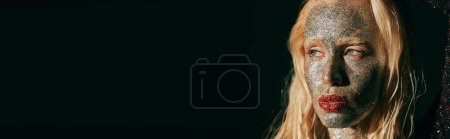 Téléchargez les photos : Bannière de jeune femme blonde avec des lèvres rouges et des étincelles brillantes sur le visage regardant loin sur fond noir - en image libre de droit