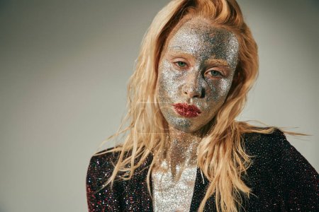portrait, pretty woman with green eyes and glitter all over body and face posing on grey backdrop