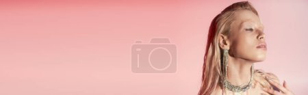 beauty banner of young blonde woman in shiny necklace and earrings posing on pink background