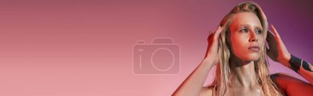 Foto de Mujer de buen aspecto en vestido rojo con estilo con tatuaje posando sobre fondo rosa y mirando hacia otro lado, pancarta - Imagen libre de derechos