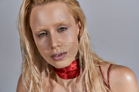 beautiful fashionable blonde woman with highlighter on face and green eyes looking at camera