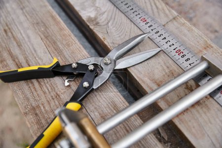 Photo for Object photo of new metal pliers lying next to measuring tape on wooden table outside of site - Royalty Free Image