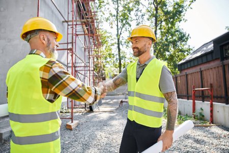 cheerful construction workers shaking their hands and smiling at each other, cottage builders