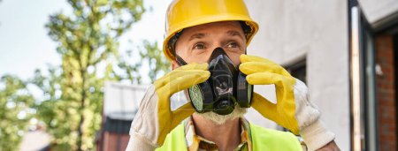 Foto de Constructor de cabaña dedicado en guantes de seguridad y máscara de polvo preparándose para su trabajo en el sitio, bandera - Imagen libre de derechos