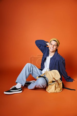 cheerful man in yellow hat sitting with backpack and putting behind head with hand