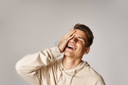 Photo for Portrait of attractive man with brown hair and grey eyes laughing and covering to face with hand - Royalty Free Image