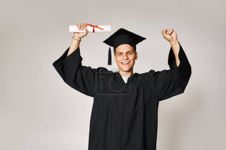 attraktive Studentin im Diplom-Outfit froh, ihr Studium auf grauem Hintergrund abgeschlossen zu haben