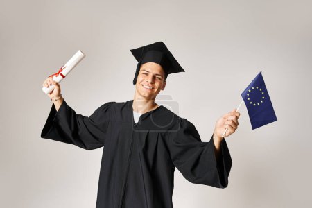 estudiante europeo en traje de graduado feliz de haber completado sus estudios sobre fondo gris