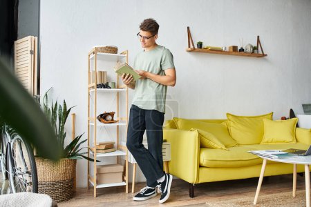 handsome student in 20s with brown hair and vision glasses in living room standing and reading book