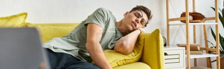 bannière de jeune homme aux cheveux bruns et lunettes de vision dormant sur canapé jaune dans le salon
