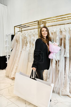 A young brunette bride stands in front of a rack of dresses in a wedding salon, carefully selecting her perfect gown.