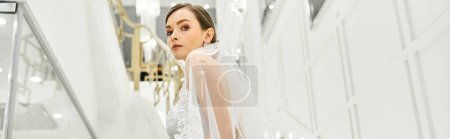 Téléchargez les photos : Une jeune mariée dans une belle robe de mariée se tient gracieusement dans un couloir - en image libre de droit