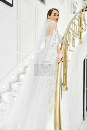 Eine junge brünette Braut im Brautkleid steht anmutig auf einer Treppe