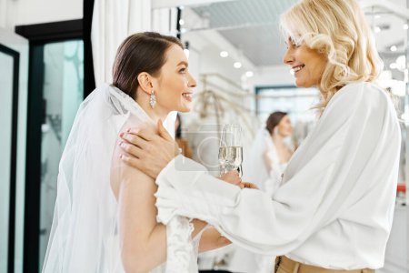 Eine junge Braut im weißen Brautkleid und ihre Mutter, beide elegant in Weiß gekleidet, stoßen mit Champagnergläsern an.